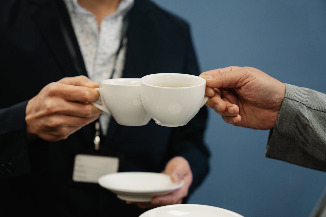 services-06 Close-up of two business professionals clinking coffee cups in an office setting.