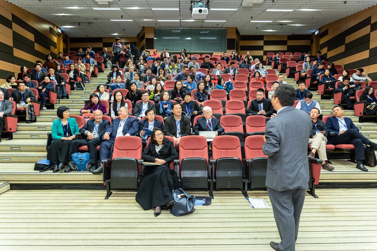 services-05 Professional setting of a business conference with attendees and a presenter in an auditorium.