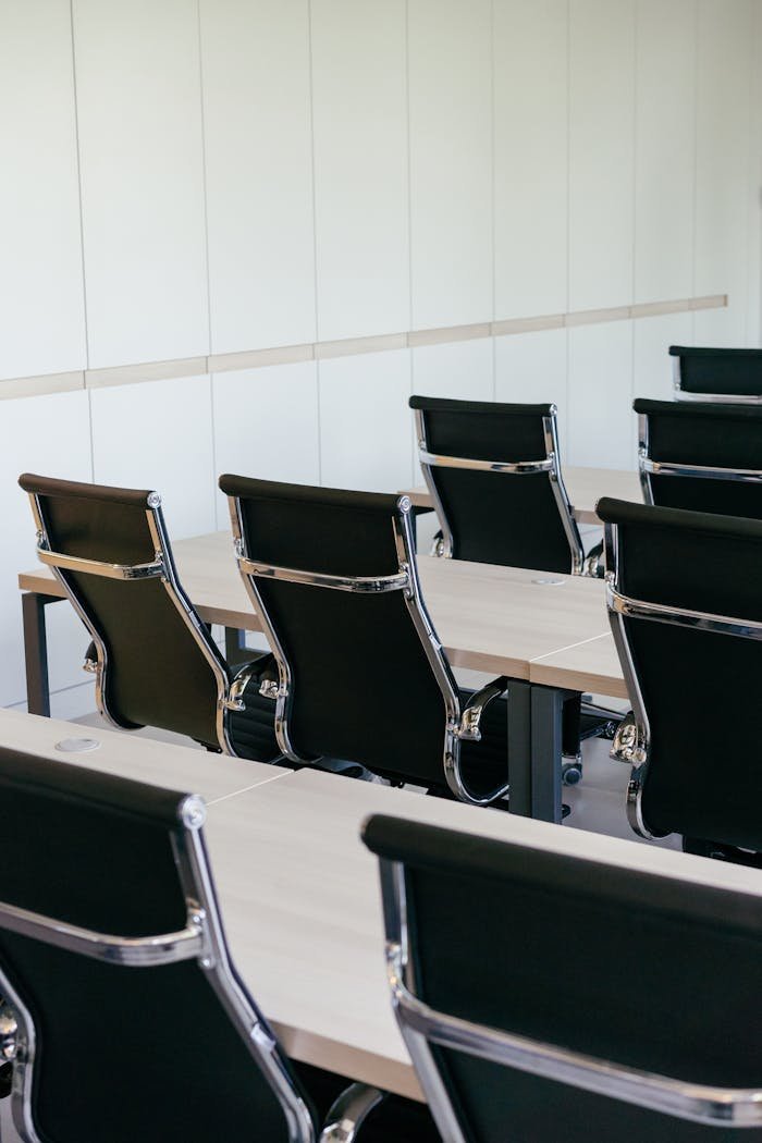 about-us Empty modern conference room with sleek black chairs and wooden desks, perfect for business meetings.